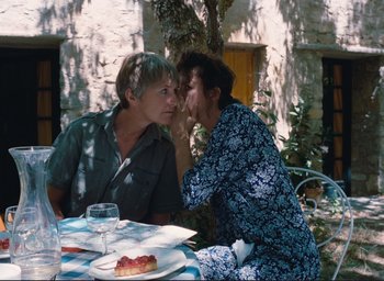 Movie still from “La Belle Noiseuse” (1991), directed by Jacques Rivette – Two people sitting at an outdoor dining table; Medium shot, High angle