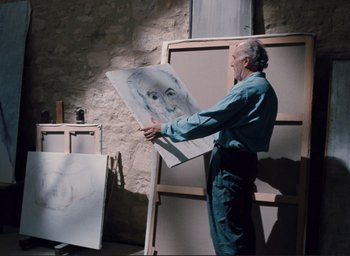 Movie still from “La Belle Noiseuse” (1991), directed by Jacques Rivette – An older man holding a painting in front of a wall; Medium shot, Low angle