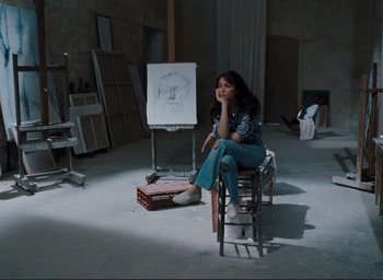 Movie still from “La Belle Noiseuse” (1991), directed by Jacques Rivette – A woman sitting on a chair in a room; Wide shot, High angle