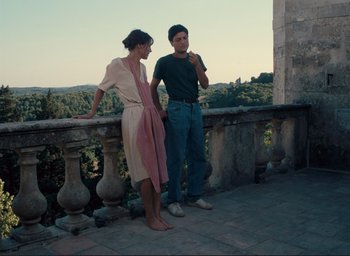 Movie still from “La Belle Noiseuse” (1991), directed by Jacques Rivette – A man and a woman standing next to a railing; Wide shot, Low angle