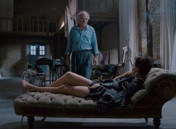 Movie still from “La Belle Noiseuse” (1991), directed by Jacques Rivette – An older man and a young woman on a couch; Wide shot, High angle
