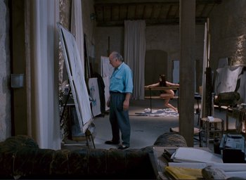 Movie still from “La Belle Noiseuse” (1991), directed by Jacques Rivette – An older man standing in front of an easel; Wide shot, Low angle