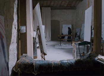 Movie still from “La Belle Noiseuse” (1991), directed by Jacques Rivette – An empty room with a lot of paintings on the walls; Wide shot, High angle