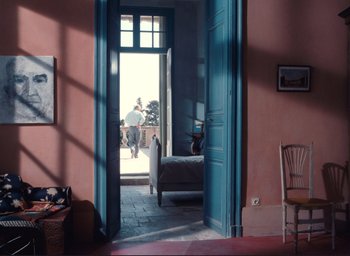 Movie still from “La Belle Noiseuse” (1991), directed by Jacques Rivette – A person is walking through a doorway to a bedroom; Wide shot, High angle