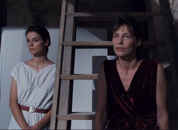 Movie still from “La Belle Noiseuse” (1991), directed by Jacques Rivette – Two women standing next to each other in front of a ladder; Medium shot, Low angle