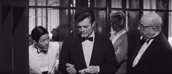 Movie still from “La Dolce Vita” (1960), directed by Federico Fellini – A black and white photo of a man smoking a cigarette; Medium shot, Over the shoulder angle