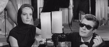 Movie still from “La Dolce Vita” (1960), directed by Federico Fellini – A woman sitting at a table next to two table lamps; Medium shot, Over the shoulder angle