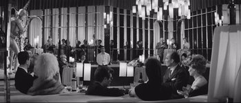 Movie still from “La Dolce Vita” (1960), directed by Federico Fellini – A group of people sitting at a table in front of a mirror; Wide shot, Over the shoulder angle