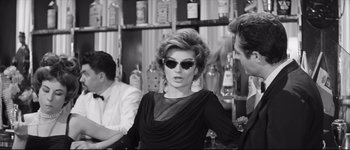 Movie still from “La Dolce Vita” (1960), directed by Federico Fellini – A black and white photo of a woman wearing sunglasses; Medium shot, Over the shoulder angle