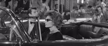 Movie still from “La Dolce Vita” (1960), directed by Federico Fellini – An older woman sitting in the back seat of a car; Medium shot, Over the shoulder angle