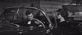 Movie still from “La Dolce Vita” (1960), directed by Federico Fellini – A black and white photo of a man in a car; Medium shot, High angle