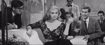 Movie still from “La Dolce Vita” (1960), directed by Federico Fellini – A black and white photo of a woman sitting on a couch; Medium shot, Low angle