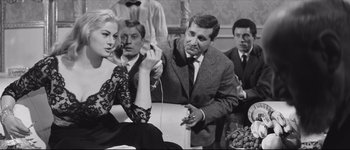 Movie still from “La Dolce Vita” (1960), directed by Federico Fellini – A man and a woman are sitting in front of another man; Medium shot, Over the shoulder angle