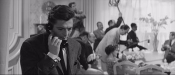 Movie still from “La Dolce Vita” (1960), directed by Federico Fellini – A black and white photo of a man talking on a phone; Medium shot, High angle