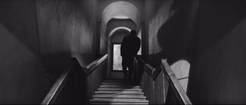 Movie still from “La Dolce Vita” (1960), directed by Federico Fellini – A man walking down a set of stairs; Wide shot, Low angle