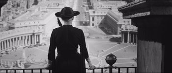 Movie still from “La Dolce Vita” (1960), directed by Federico Fellini – A woman wearing a hat looking out over a city; Medium shot, Over the shoulder angle