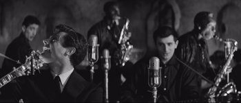Movie still from “La Dolce Vita” (1960), directed by Federico Fellini – A black and white photo of a group of men singing; Medium shot, Over the shoulder angle