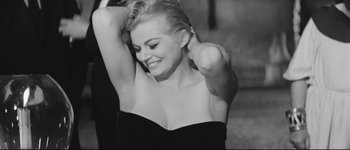 Movie still from “La Dolce Vita” (1960), directed by Federico Fellini – A woman in a strapless top smiling for the camera; Close Up shot, High angle
