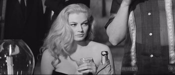 Movie still from “La Dolce Vita” (1960), directed by Federico Fellini – A black and white photo of a woman holding a drink; Close Up shot, Over the shoulder angle