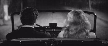 Movie still from “La Dolce Vita” (1960), directed by Federico Fellini – A man and a woman sitting in the back seat of a car; Medium shot, High angle