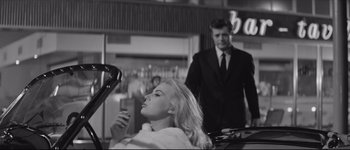 Movie still from “La Dolce Vita” (1960), directed by Federico Fellini – A woman blow drying her hair in front of a man; Medium shot, Low angle