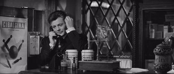 Movie still from “La Dolce Vita” (1960), directed by Federico Fellini – A black and white photo of a man talking on the phone; Medium shot, Low angle