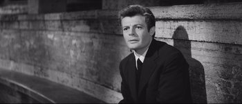 Movie still from “La Dolce Vita” (1960), directed by Federico Fellini – Black and white photograph of a man wearing a suit; Close Up shot, Low angle