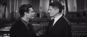 Movie still from “La Dolce Vita” (1960), directed by Federico Fellini – Two men in suits shaking hands in front of a bar; Close Up shot, Over the shoulder angle