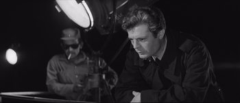 Movie still from “La Dolce Vita” (1960), directed by Federico Fellini – Black and white photograph of a man in a suit and tie; Close Up shot, Over the shoulder angle