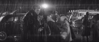 Movie still from “La Dolce Vita” (1960), directed by Federico Fellini – A man and a woman standing in the pouring rain; Medium shot, High angle
