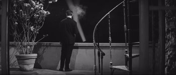 Movie still from “La Dolce Vita” (1960), directed by Federico Fellini – A man in a black suit standing in front of a balcony; Wide shot, High angle
