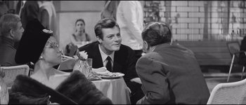 Movie still from “La Dolce Vita” (1960), directed by Federico Fellini – A man sitting at a table with two other men; Medium shot, Over the shoulder angle