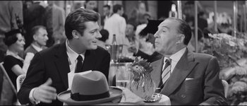 Movie still from “La Dolce Vita” (1960), directed by Federico Fellini – Two men sitting at a table talking to each other; Medium shot, Over the shoulder angle