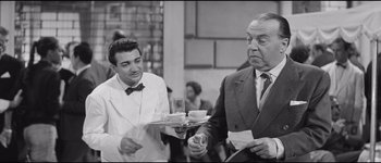 Movie still from “La Dolce Vita” (1960), directed by Federico Fellini – A man holding a tray of food next to another man holding a cup; Medium shot, Over the shoulder angle