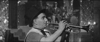 Movie still from “La Dolce Vita” (1960), directed by Federico Fellini – An older man holding a trumpet in front of a group of men; Medium shot, Low angle