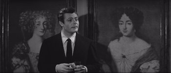 Movie still from “La Dolce Vita” (1960), directed by Federico Fellini – A black and white photo of a man in a suit holding a glass; Close Up shot, Over the shoulder angle