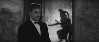 Movie still from “La Dolce Vita” (1960), directed by Federico Fellini – A black and white photo of a man in a tuxedo; Medium shot, Over the shoulder angle