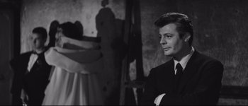 Movie still from “La Dolce Vita” (1960), directed by Federico Fellini – A black and white photo of a man in a suit and tie; Close Up shot, Over the shoulder angle