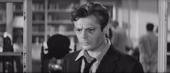 Movie still from “La Dolce Vita” (1960), directed by Federico Fellini – Black and white photograph of a man in a suit and tie; Close Up shot, Over the shoulder angle