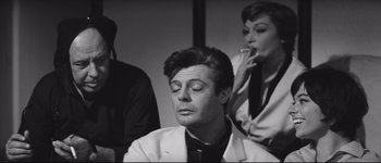 Movie still from “La Dolce Vita” (1960), directed by Federico Fellini – A black and white photo of a man and two women smoking cigarettes; Close Up shot, Over the shoulder angle