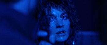 Movie still from “Nikita” (1990), directed by Luc Besson – A person holding a gun in a room; Close Up shot, Low angle