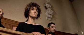 Movie still from “Nikita” (1990), directed by Luc Besson – A woman and a man are standing in front of a statue; Close Up shot, Low angle