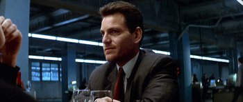 Movie still from “Nikita” (1990), directed by Luc Besson – A person wearing a suit holding a wine glass; Close Up shot, Low angle