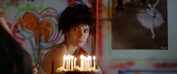 Movie still from “Nikita” (1990), directed by Luc Besson – A person with a birthday cake with lit candles; Close Up shot, Low angle