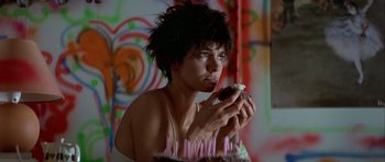 Movie still from “Nikita” (1990), directed by Luc Besson – A woman sitting in front of a table with a cake; Close Up shot, Low angle