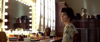 Movie still from “Nikita” (1990), directed by Luc Besson – A woman sitting at a table in front of a window; Medium shot, Over the shoulder angle