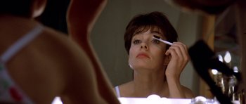 Movie still from “Nikita” (1990), directed by Luc Besson – A woman looking in a mirror while holding a brush; Close Up shot, Low angle