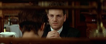 Movie still from “Nikita” (1990), directed by Luc Besson – A man in a suit looking at himself in the mirror; Close Up shot, Over the shoulder angle