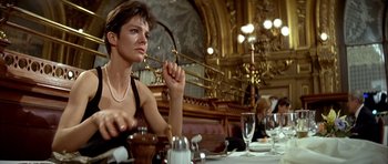 Movie still from “Nikita” (1990), directed by Luc Besson – A woman sitting at a table in a restaurant; Medium shot, Low angle
