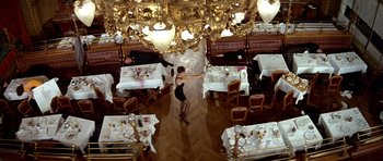 Movie still from “Nikita” (1990), directed by Luc Besson – A woman in a black dress is dancing in a restaurant; Wide shot, High angle